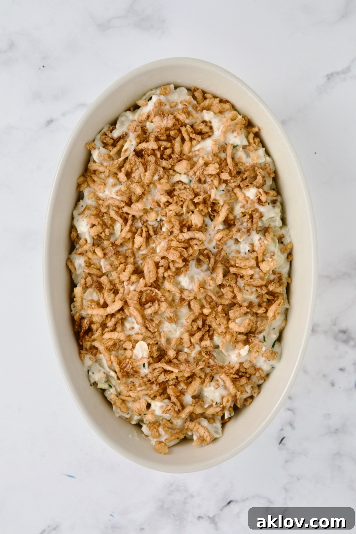 Crispy French-fried onions liberally sprinkled over the creamy cabbage in an oval white baking dish, creating a delicious crust.