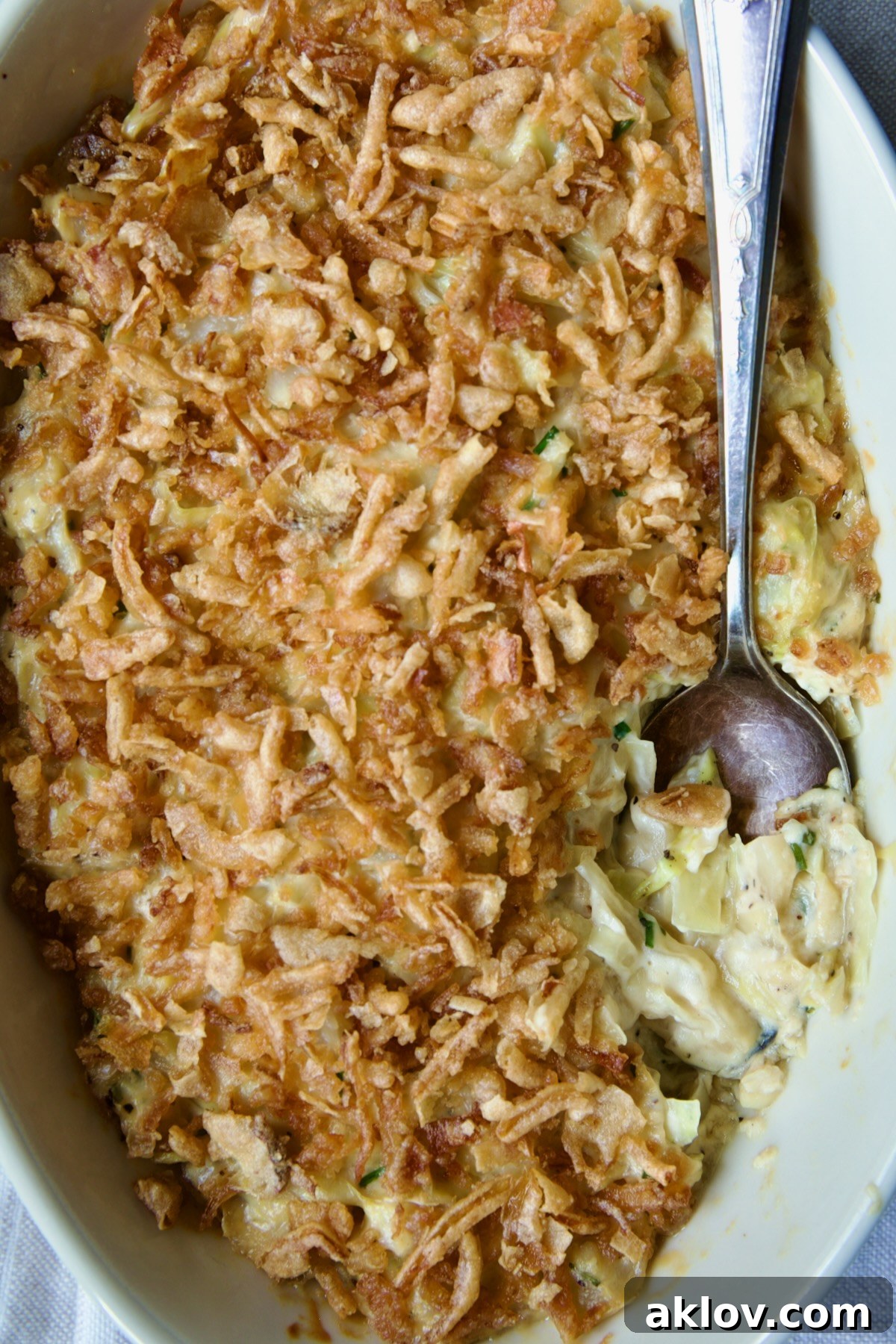 A vibrant, close-up shot of the Creamed Cabbage Casserole, showcasing its rich, creamy texture and inviting presentation in a white oval baking dish with a serving spoon.