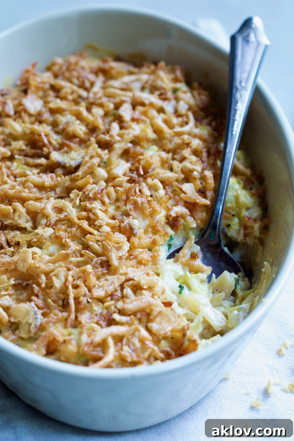 A top-down view of the Creamed Cabbage Casserole in a white oval baking dish, showcasing its inviting texture and golden crispy onion topping, ready to be served.