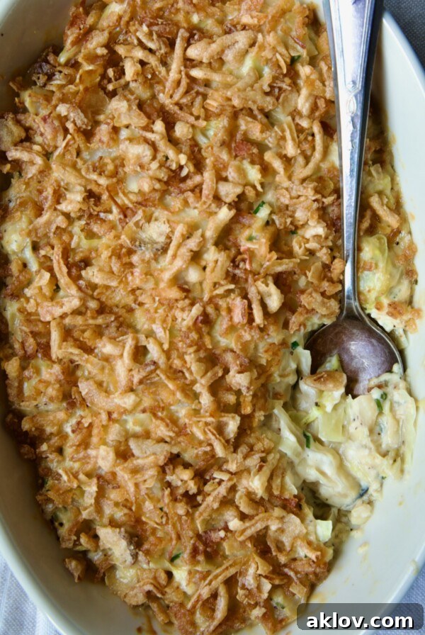 Creamed Cabbage Casserole in white oval baking dish with ornate serving spoon.