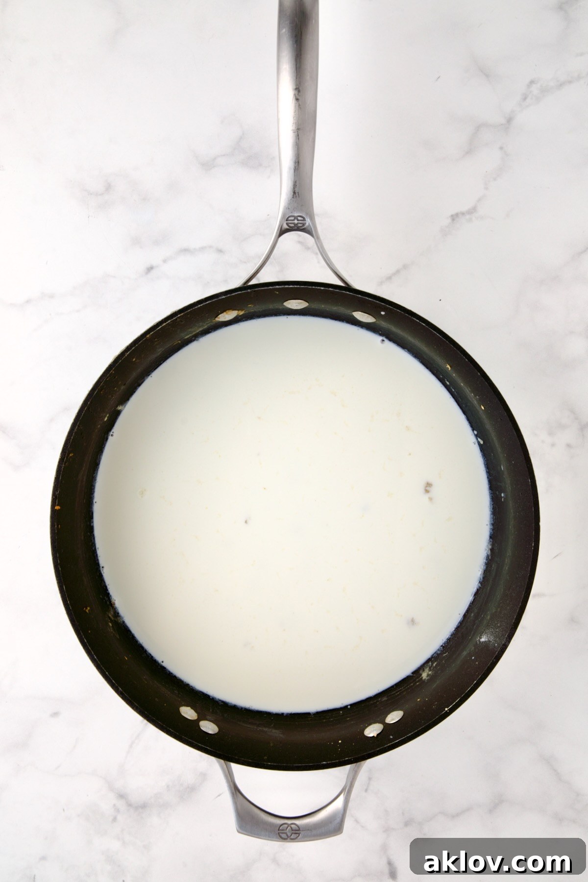 Half-and-half being poured into a nonstick skillet, slowly combining with the roux to create a smooth, rich, and creamy sauce.