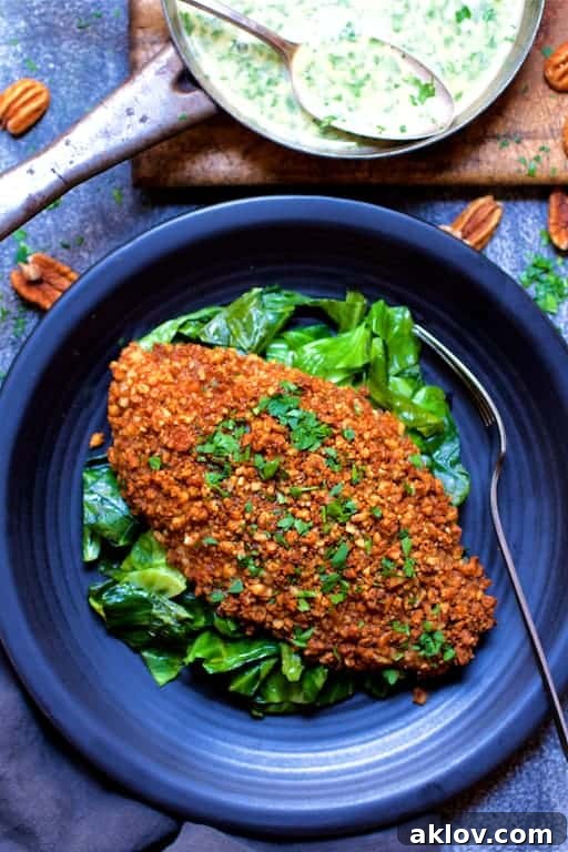 Photo of Baked Catfish Pecan Meuniere with Spicy Sauteed Greens on black plate.
