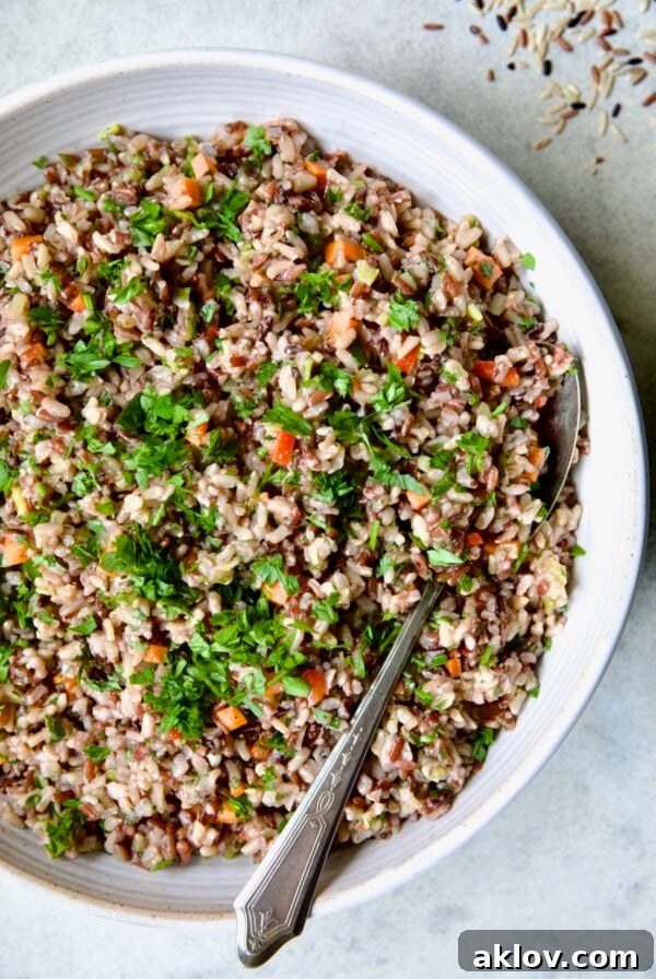 Wild Rice Pilaf in white serving bowl with serving spoon.
