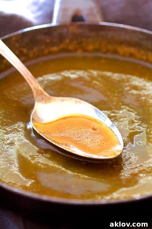 Close-up photo of perfectly browned butter with its characteristic nutty milk solids settled at the bottom of a small saucepan.