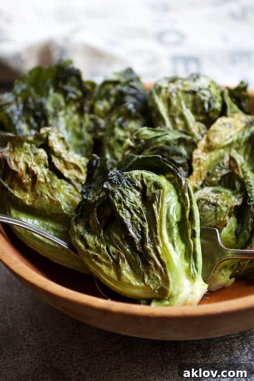 Close-up photo of perfectly roasted Duck Fat Cabbage Sprouts, showcasing their crispy edges, in a wooden serving bowl.