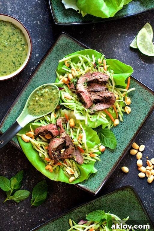 A beautifully arranged plate of Thai Beef Lettuce Wraps with Mint Dressing and Vegetable Slaw on green square plates, showcasing fresh ingredients.