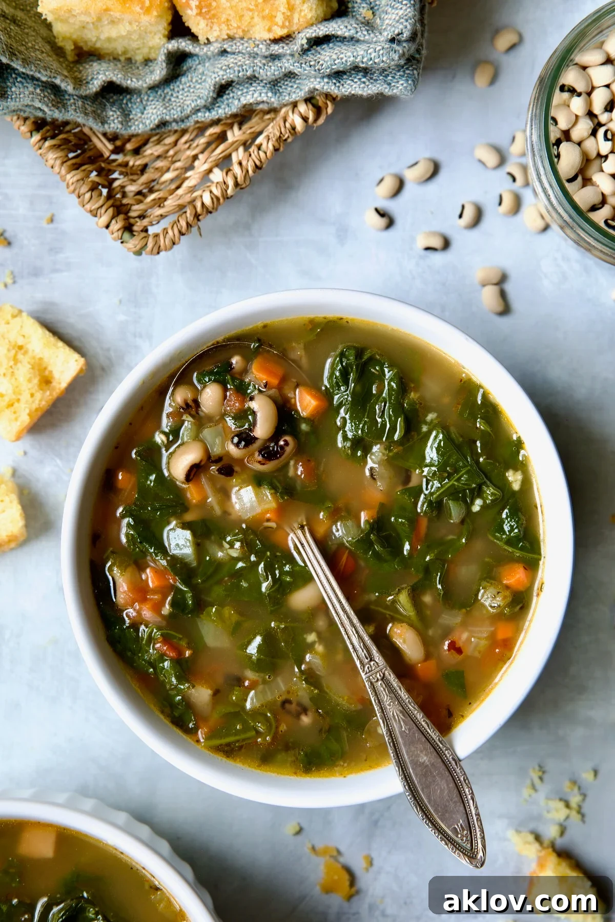 One serving of Black-Eyed Pea Soup in a white bowl with cornbread in a basket.