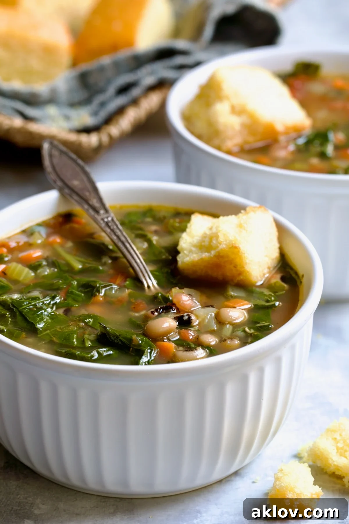 Two servings of Black-Eyed Pea Soup in white bowls with cornbread on top.