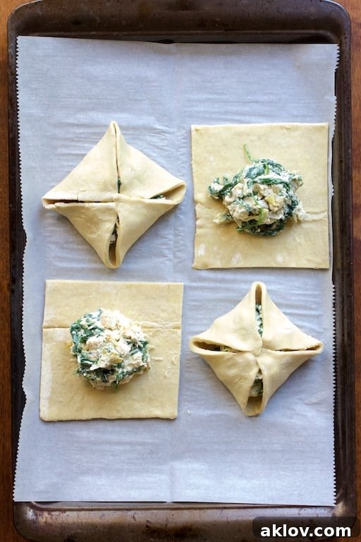 Photo of four parcels on parchment paper-lined baking sheet with filling--two folded, two not yet folded before baking.