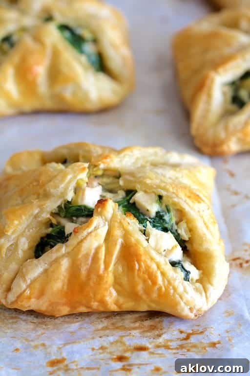 Close-up photo of Chicken Spinach and Artichoke Puff Pastry Parcels on parchment paper.