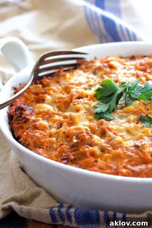 Spaghetti Bake Delight 2 A beautifully baked Spaghetti Pie with Three Cheeses, golden brown and bubbling, served in a white baking dish on a blue striped towel, ready to be enjoyed.
