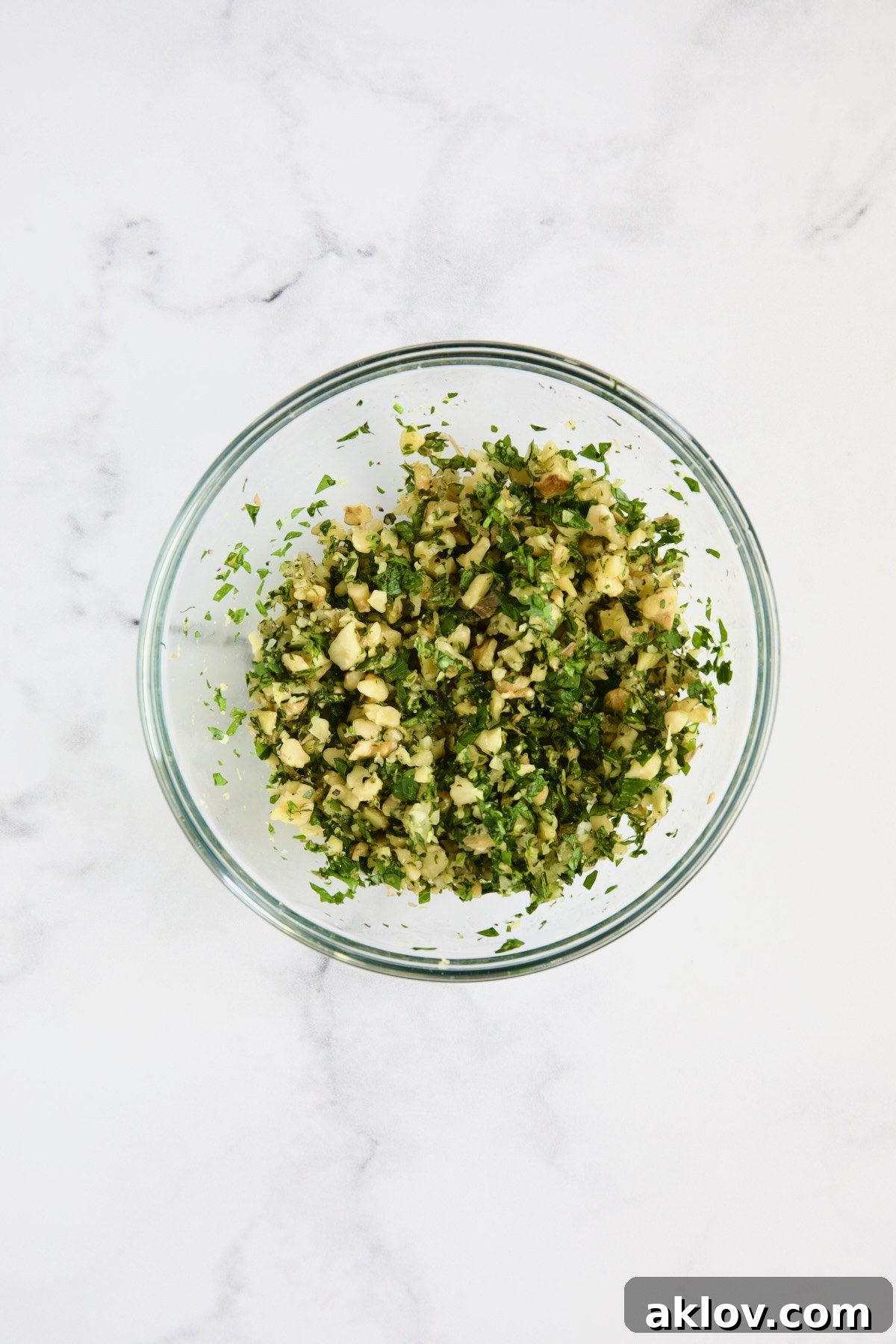 A small glass bowl filled with freshly prepared Walnut Lemon Gremolata, vibrant and fragrant.
