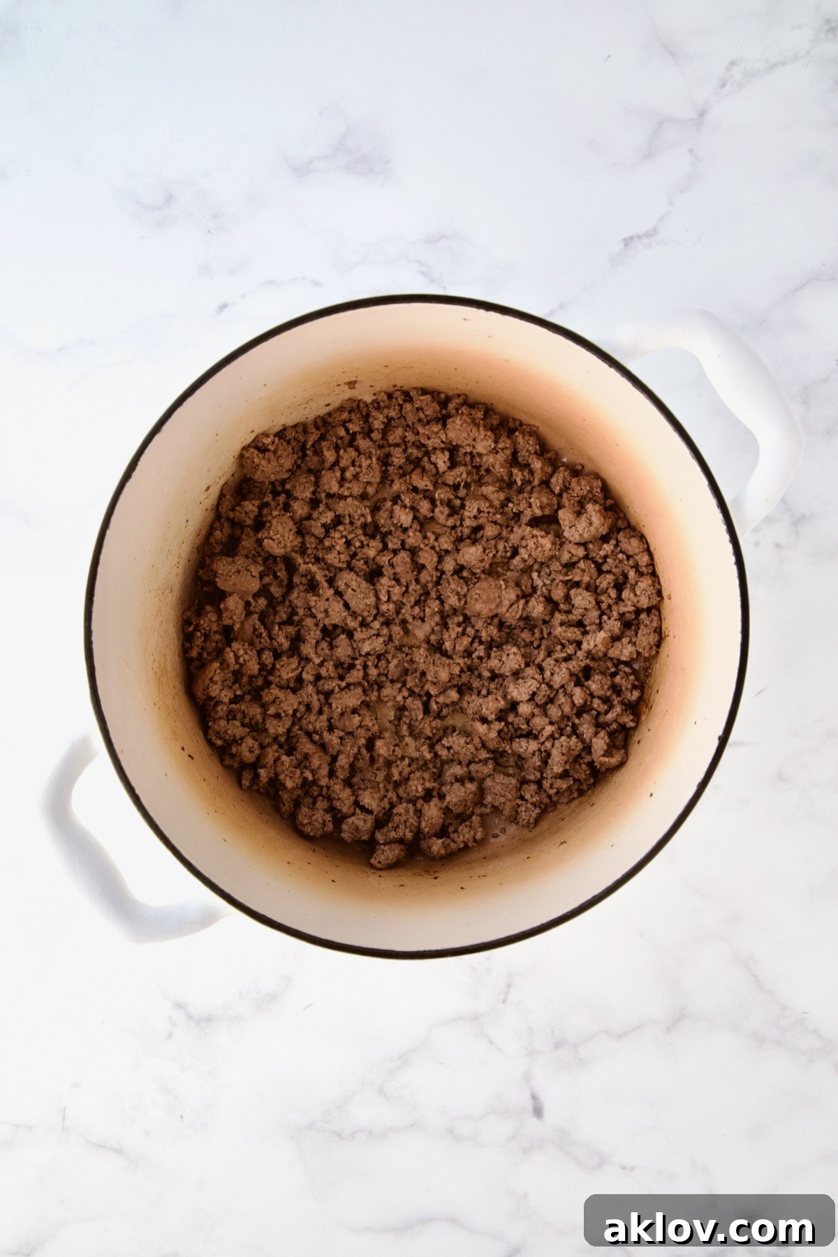 Cooked ground beef in white Dutch oven.