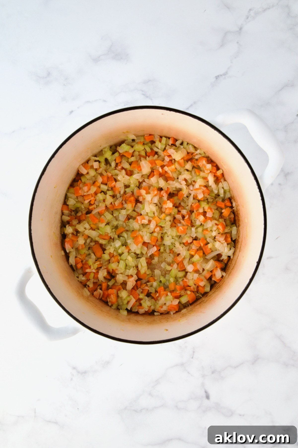 Cooked onions, carrots and celery in white Dutch oven.