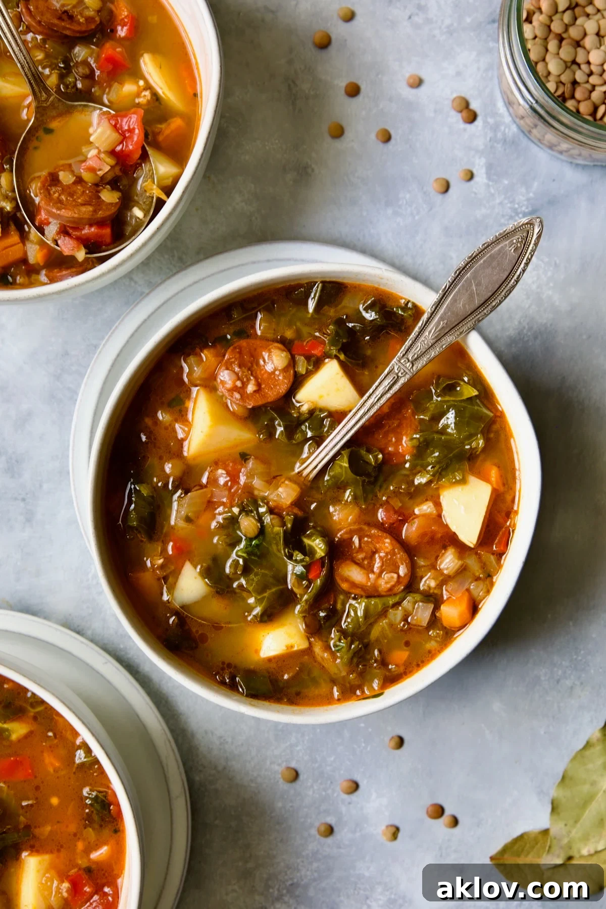 One serving of Spanish Lentil Potato Soup in white bowl with soup spoon.