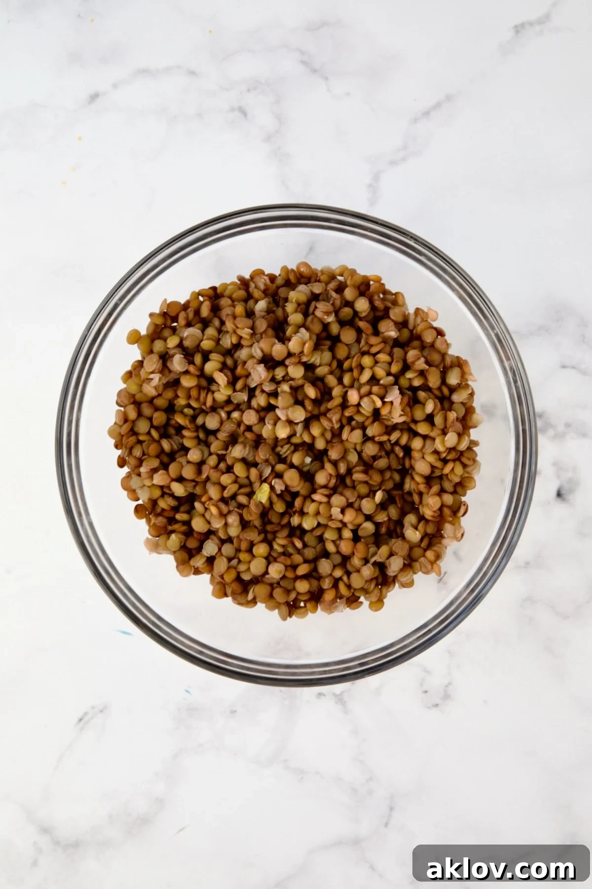 Cooked brown lentils in glass bowl.