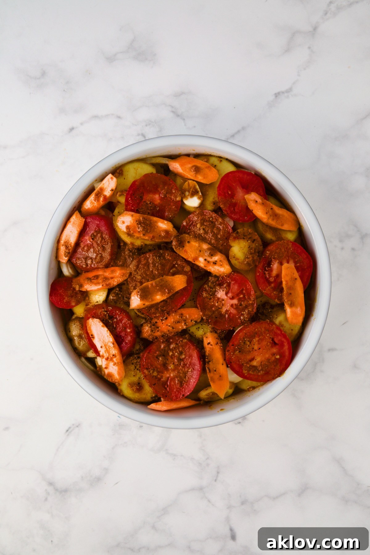 Assembled tagine before being baked in round white baking dish.