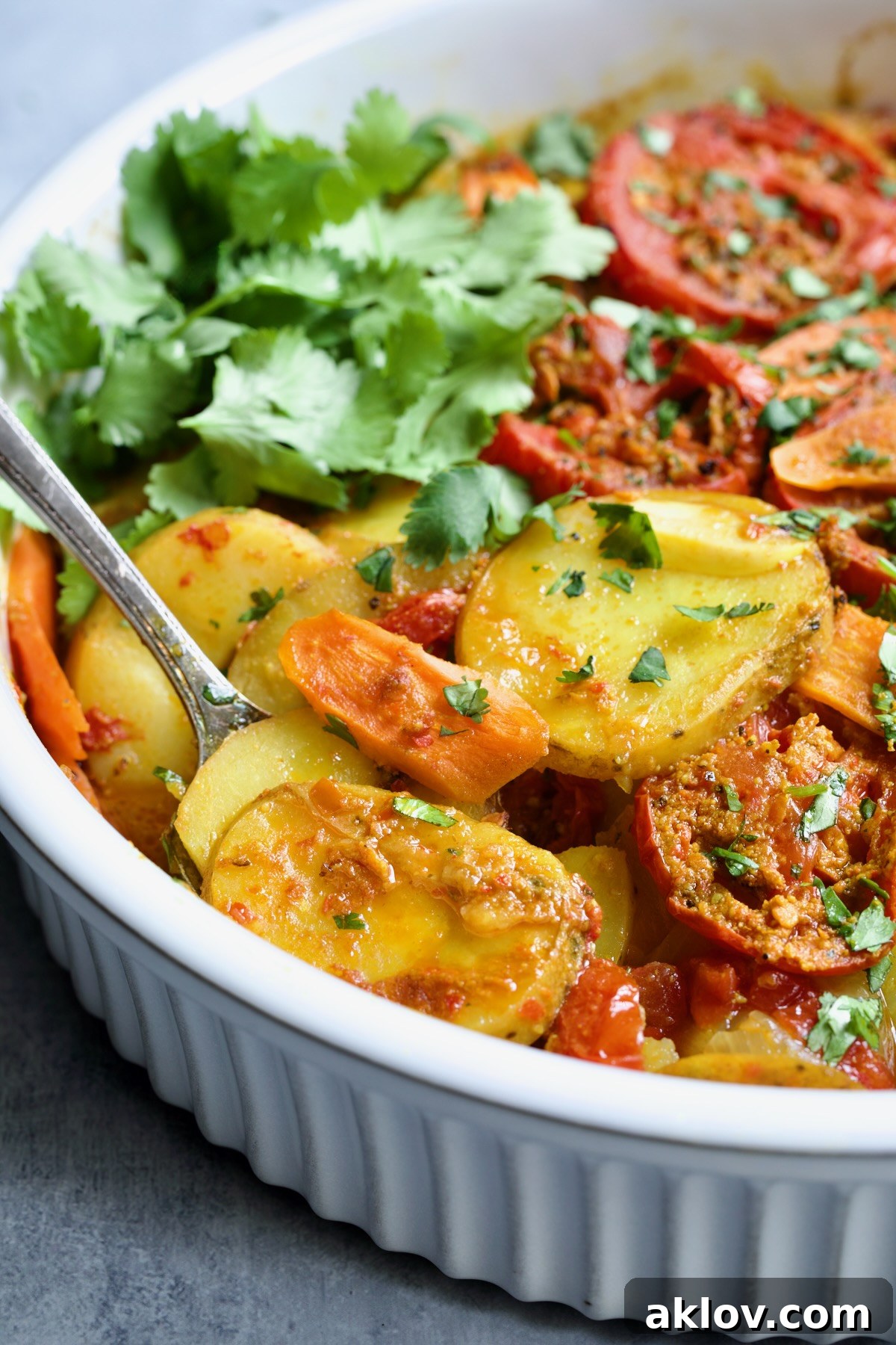 Moroccan Potato Tagine in round white baking dish with serving fork lifting some out.