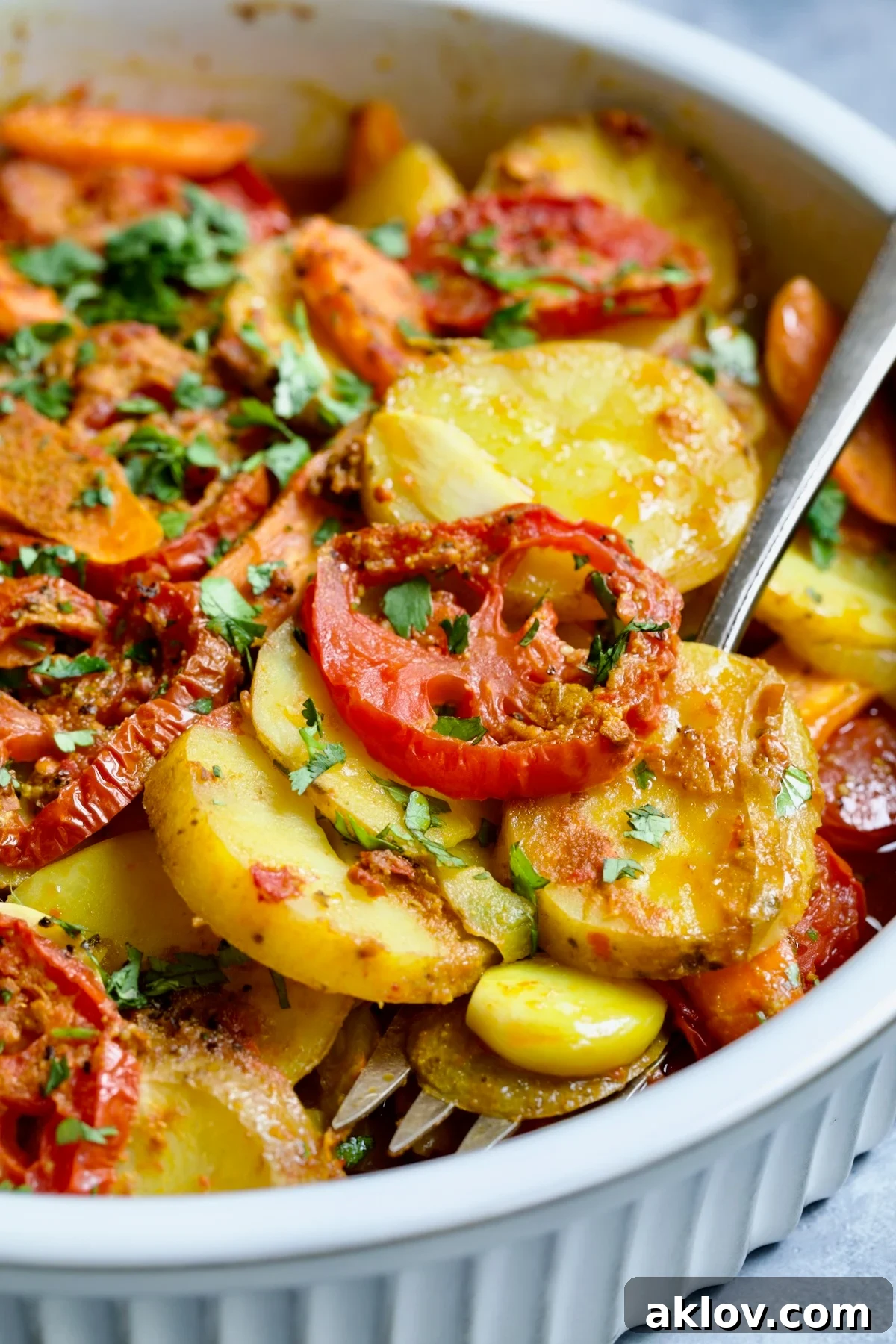 Moroccan Potato Tagine in round white baking dish with serving fork lifting some out.