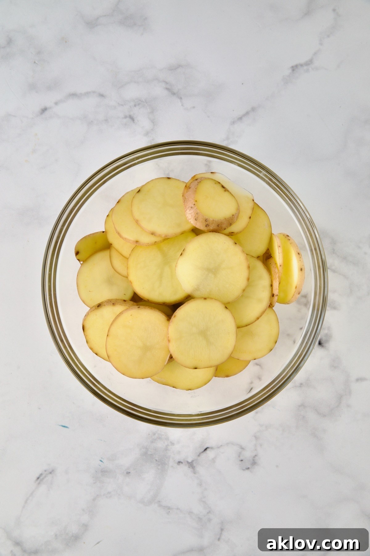 Sliced potatoes in glass bowl.
