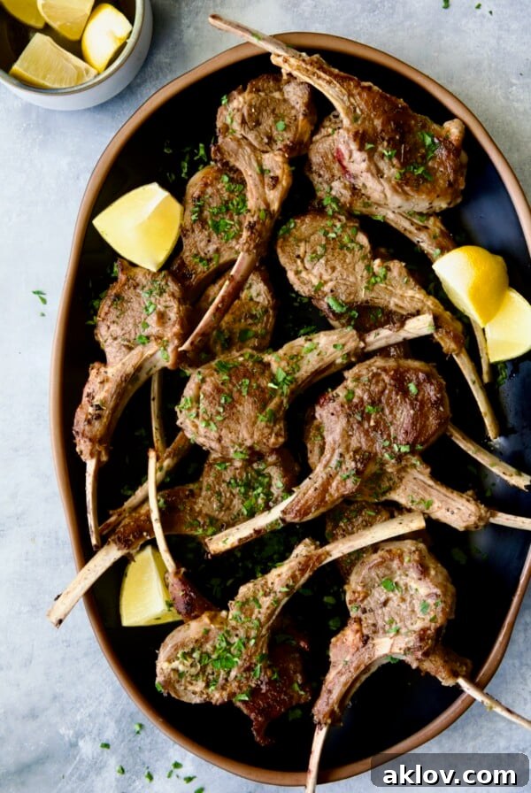 Greek Lamb Chops on black oval platter garnished with lemon wedges.
