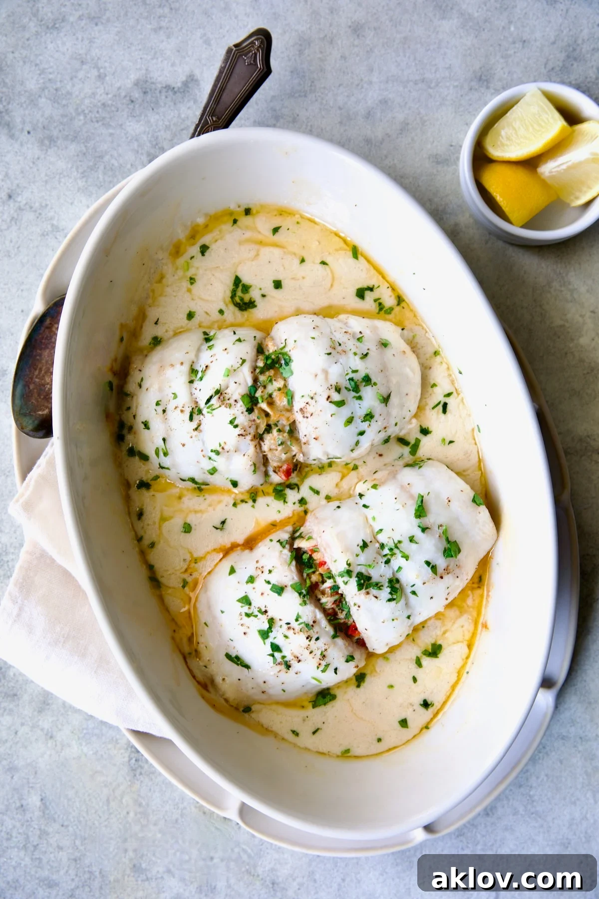 Two baked servings of Crab-Stuffed Flounder nestled in an oval baking dish, golden and hot from the oven.