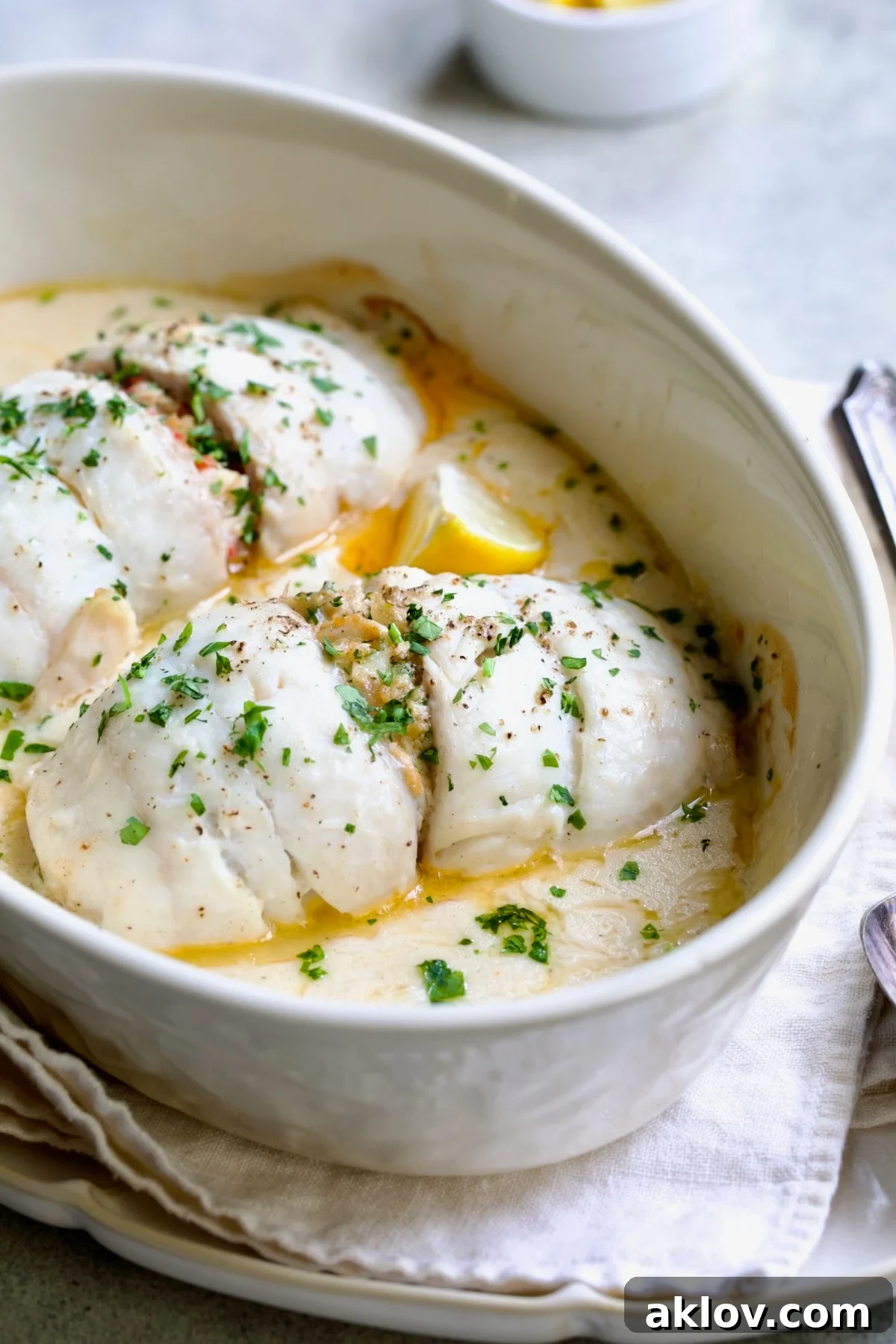 Two servings of Crab-Stuffed Flounder baking in an oval gratin dish, with a rich, creamy sauce.