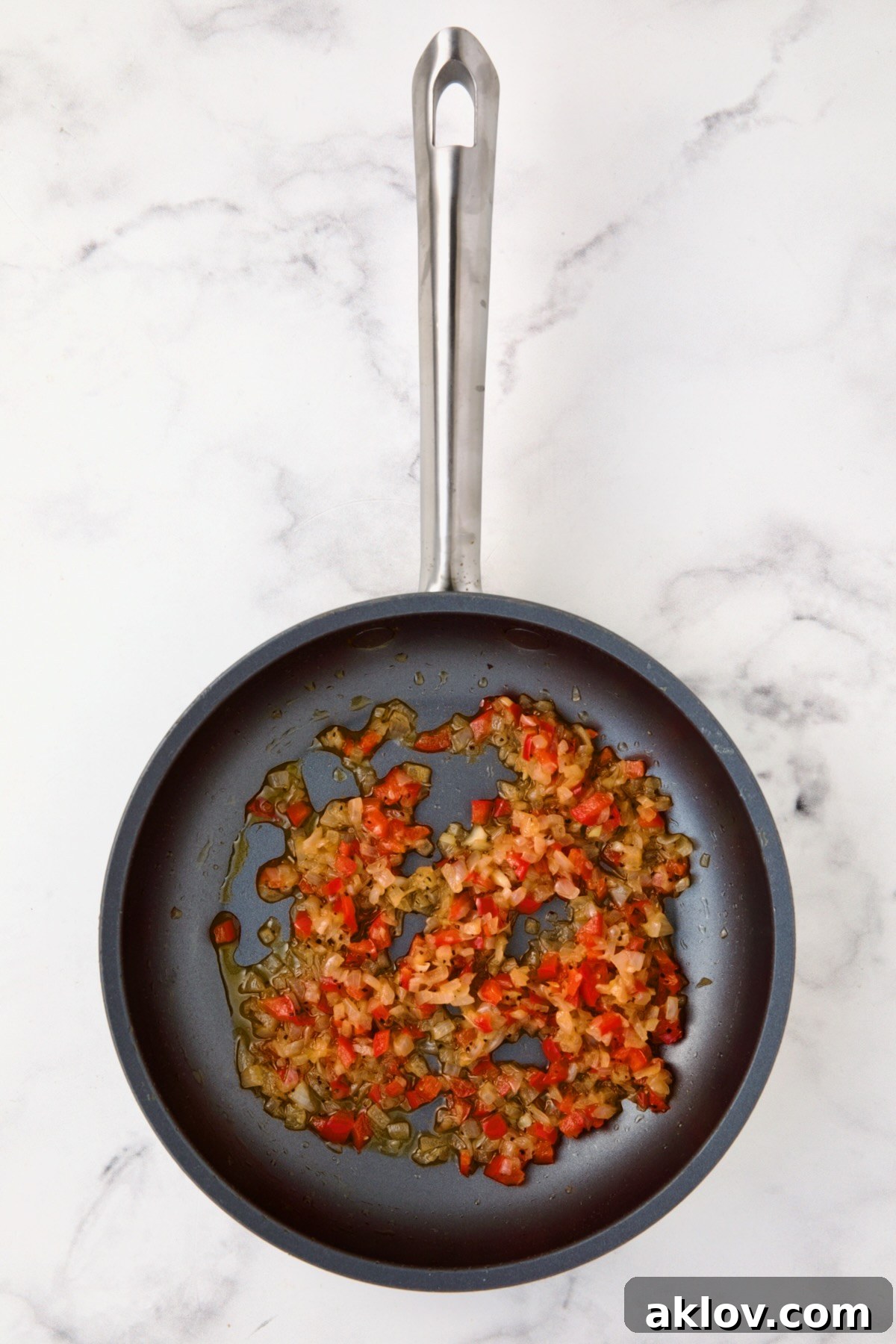 Finely chopped shallot and red bell pepper gently cooking in butter in a nonstick skillet.