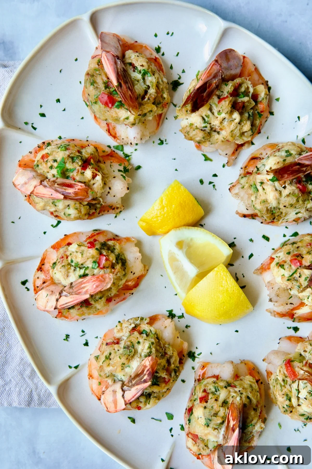 Crab-Stuffed Shrimp on an oval white platter garnished with fresh parsley and vibrant lemon wedges, ready to be served.
