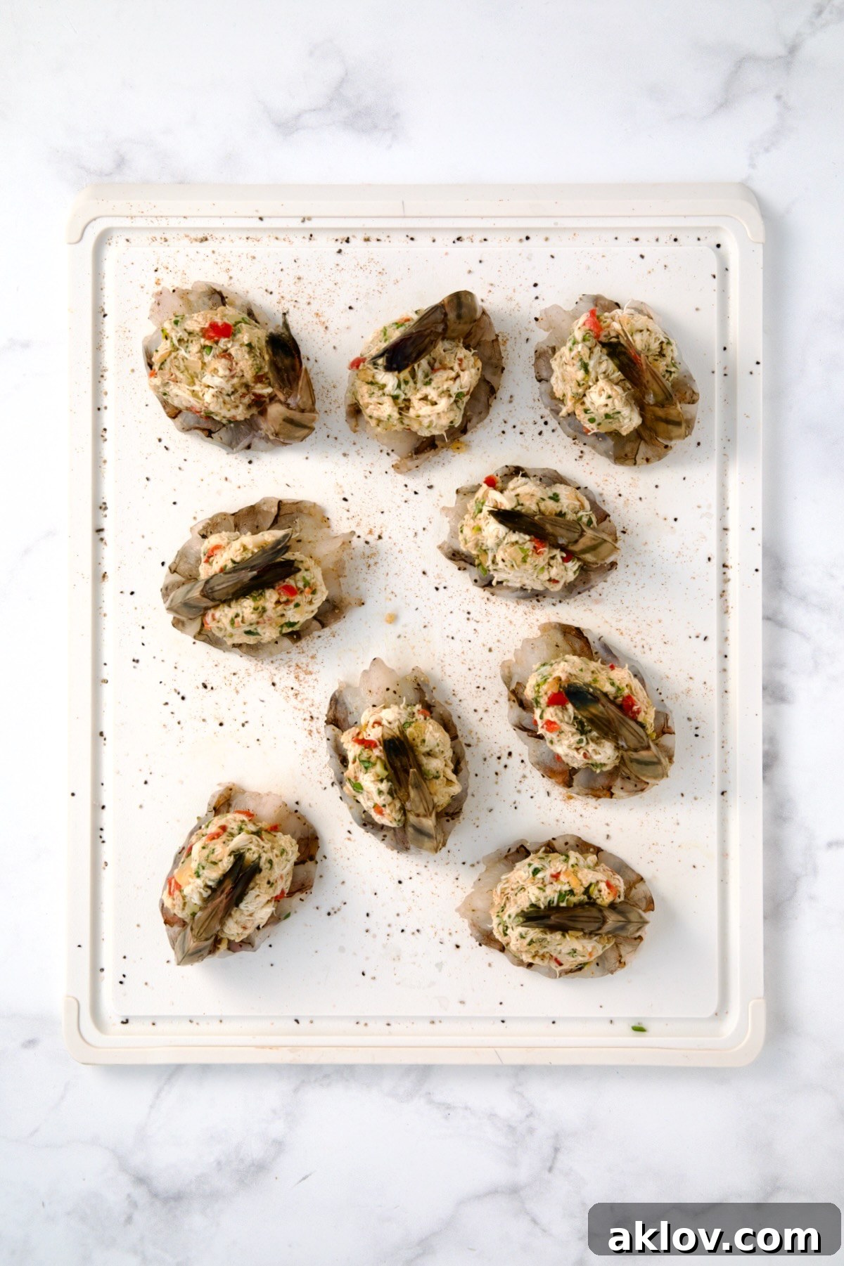 Nine stuffed shrimp on a white plastic cutting board, after being filled with the delicious crab mixture.