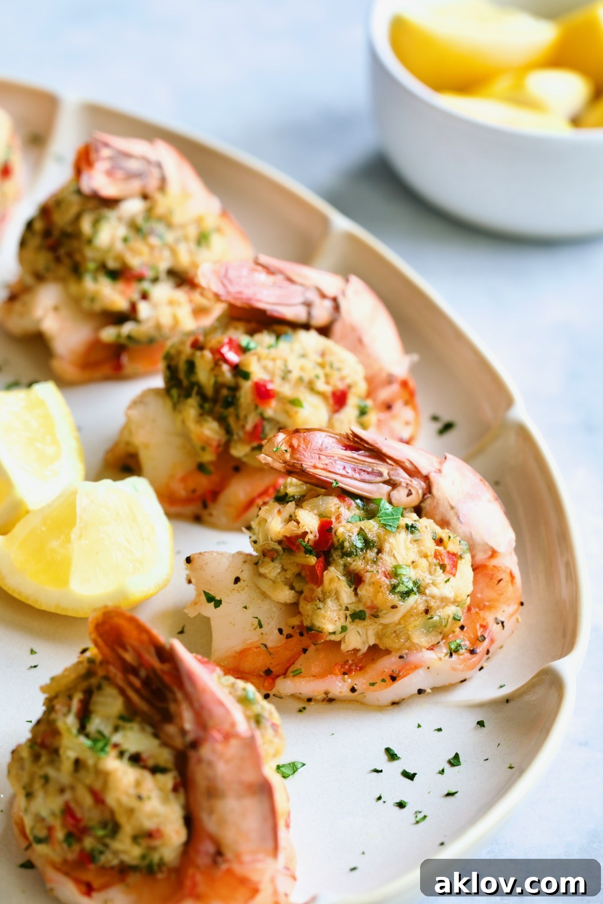 A close-up of Crab-Stuffed Shrimp on an oval white platter, beautifully garnished with parsley and lemon wedges.