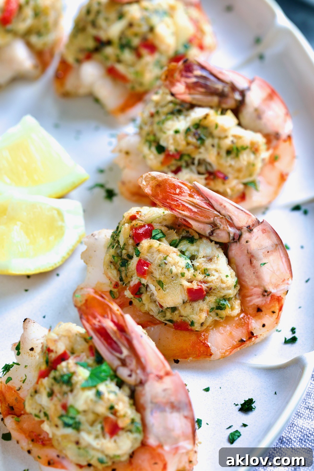 Crab-Stuffed Shrimp on an oval white platter, garnished with fresh parsley and lemon wedges, showcasing its golden-brown finish.