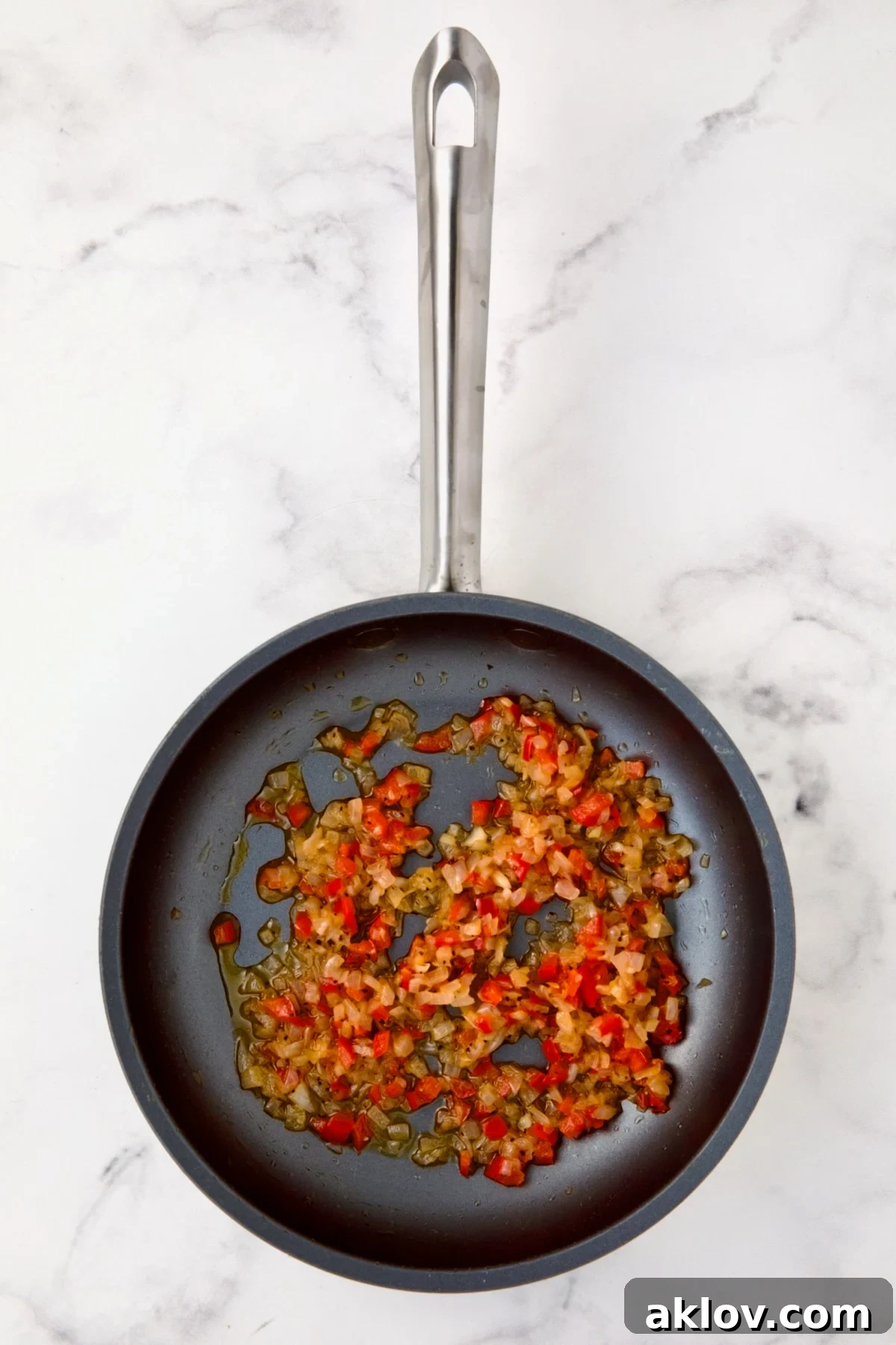 Cooked shallots and red bell pepper in a nonstick skillet, softened and ready for the crab filling.