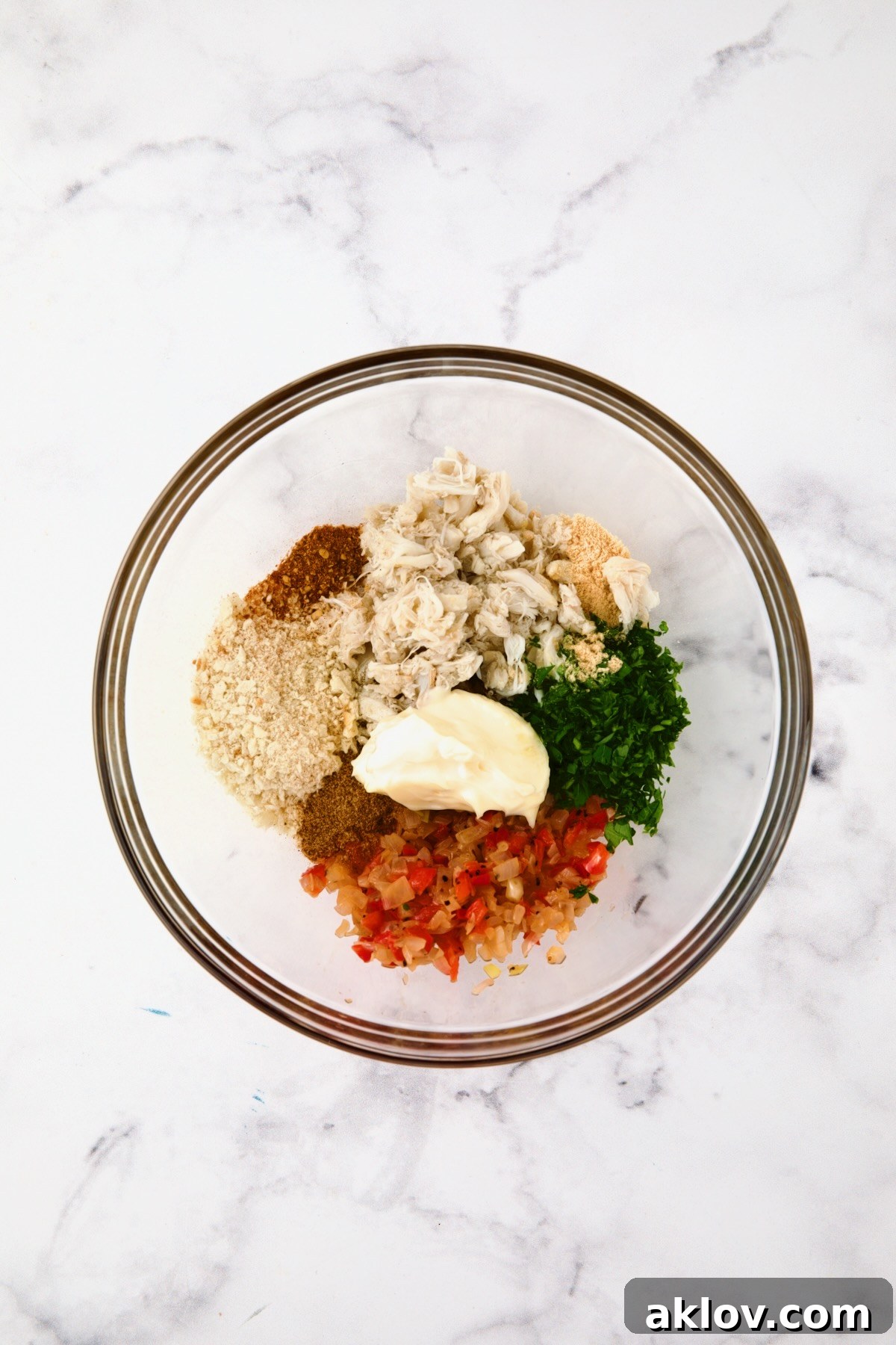 Ingredients for Crab-Stuffed Shrimp filling being combined in a clear glass bowl, showing the texture and colors.