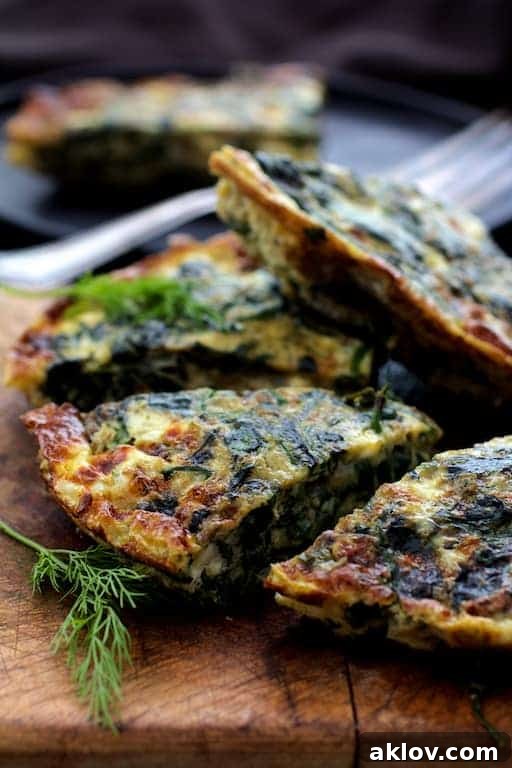 Mediterranean Greens and Feta Frittata 7 Close-up photo of frittata wedges on wood cutting board garnished with fresh dill. A close-up view of beautifully cut frittata wedges on a wooden board, elegantly garnished with fresh dill, ready to be savored.