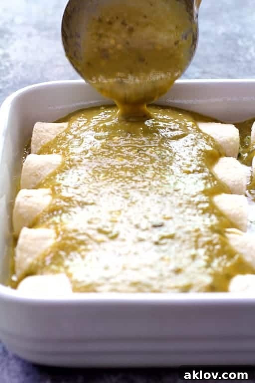 Photo of green chile sauce being poured over enchiladas.