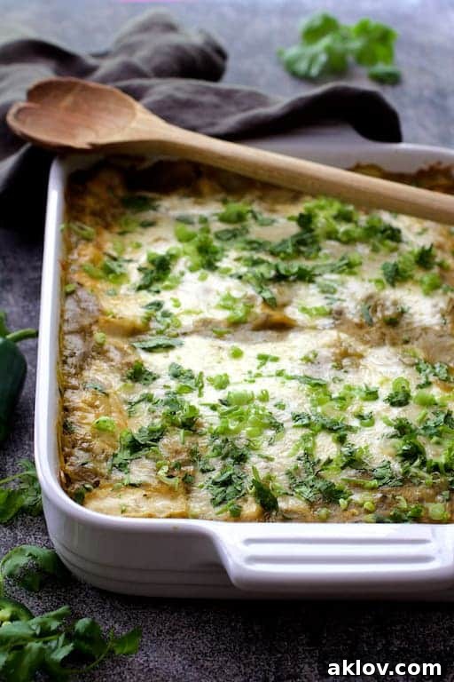 Photo of Lima Bean and Potato Enchiladas with Hatch Green Chile Sauce in white baking dish with wood serving spoon.