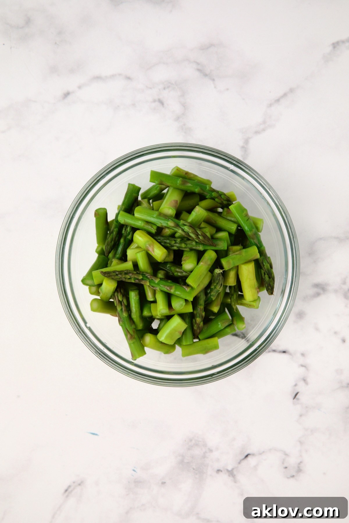 Blanched and cooled asparagus pieces, vibrant green, drained and patted dry in a glass bowl, ready for the Lemony Lentil Salad.