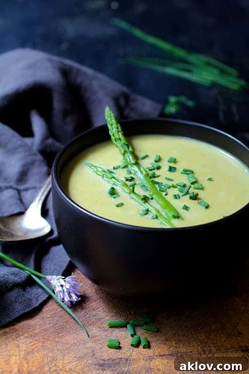 Cream of Asparagus Soup with Curry in black bowl garnished with fresh chives.