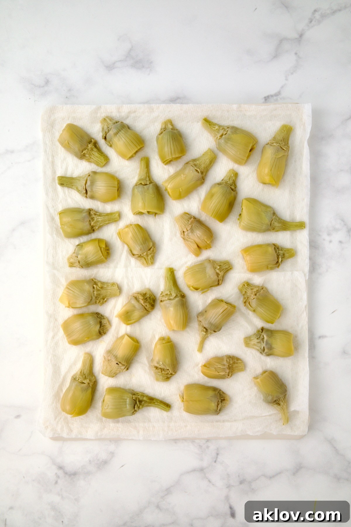 Halved artichoke hearts being drained on paper towels.