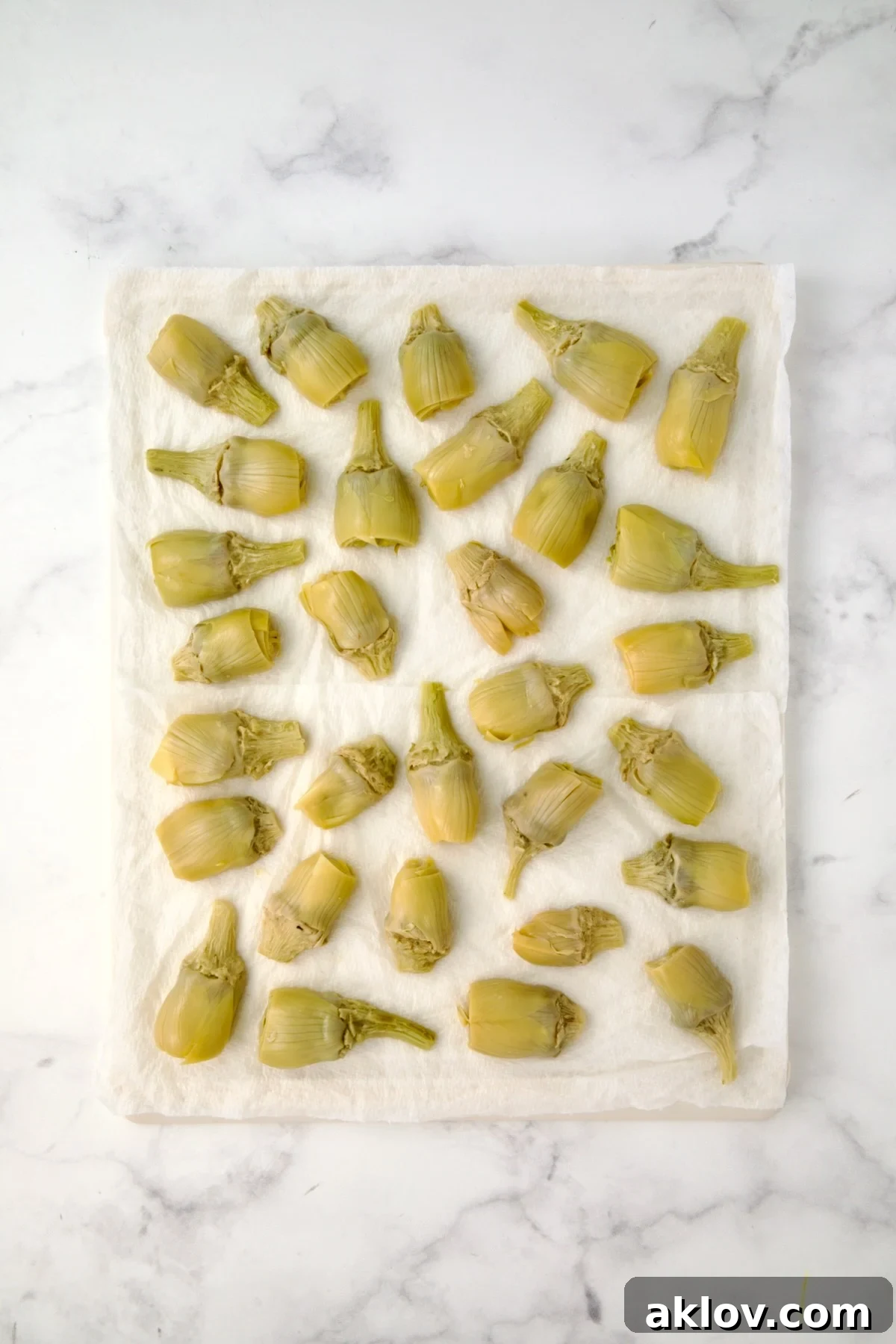 Halved artichoke hearts being drained on paper towels.