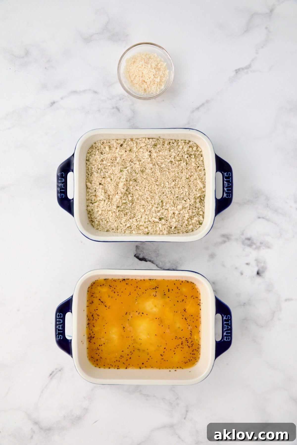 Three containers with parmesan cheese in one, breadcrumbs in another and eggs in a third.