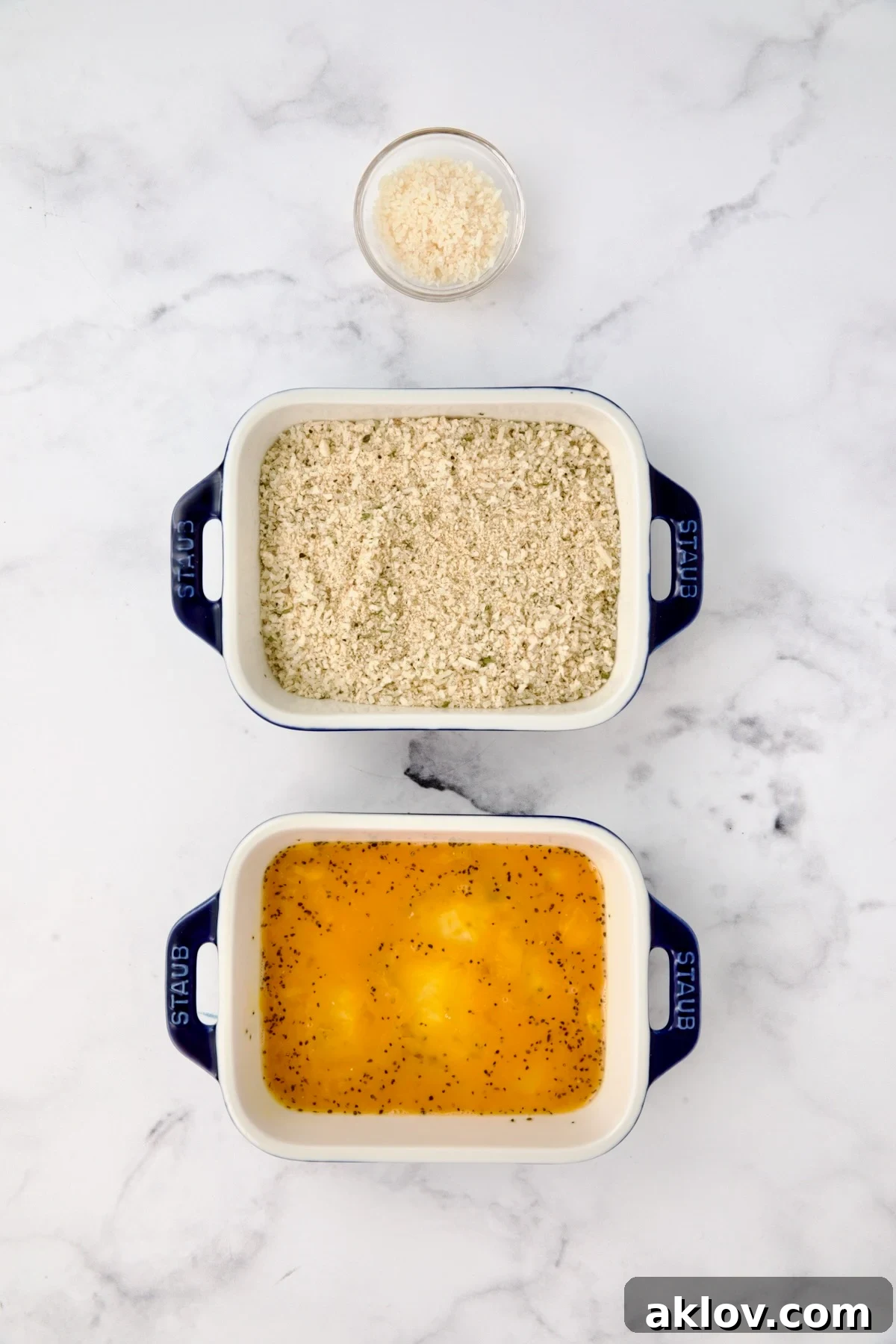 Three containers with parmesan cheese in one, breadcrumbs in another and eggs in a third.