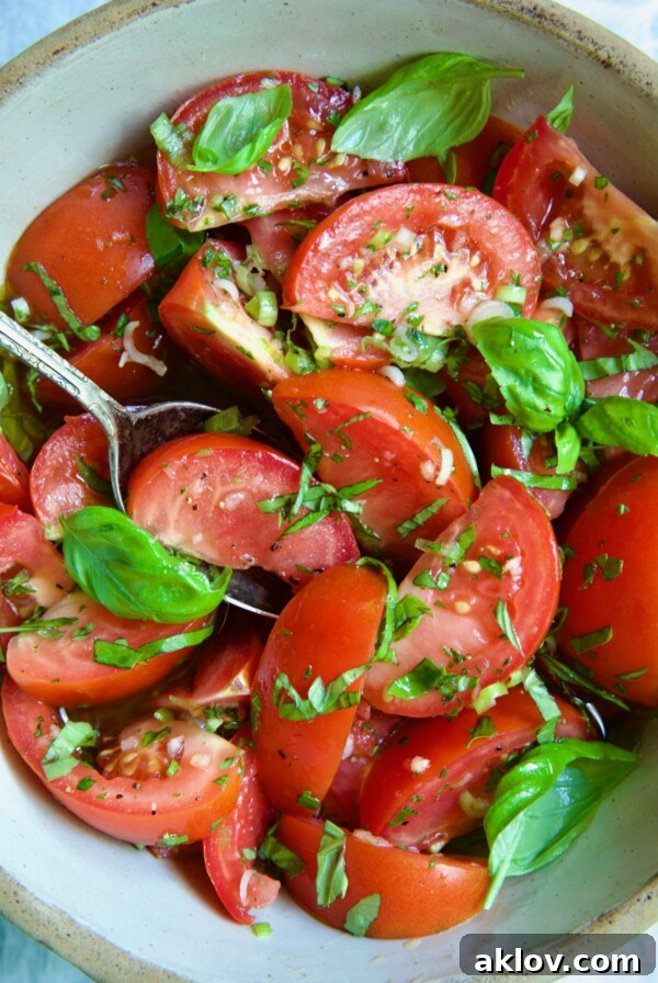 Marinated Tomatoes in old clay bowl with serving spoon garnished with fresh parsley.