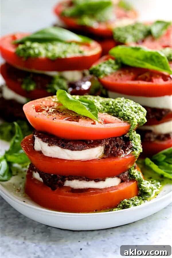 Stacked Tomato Salad with Tapenade and Basil Pesto Dressing - Close-up hero shot on white platter
