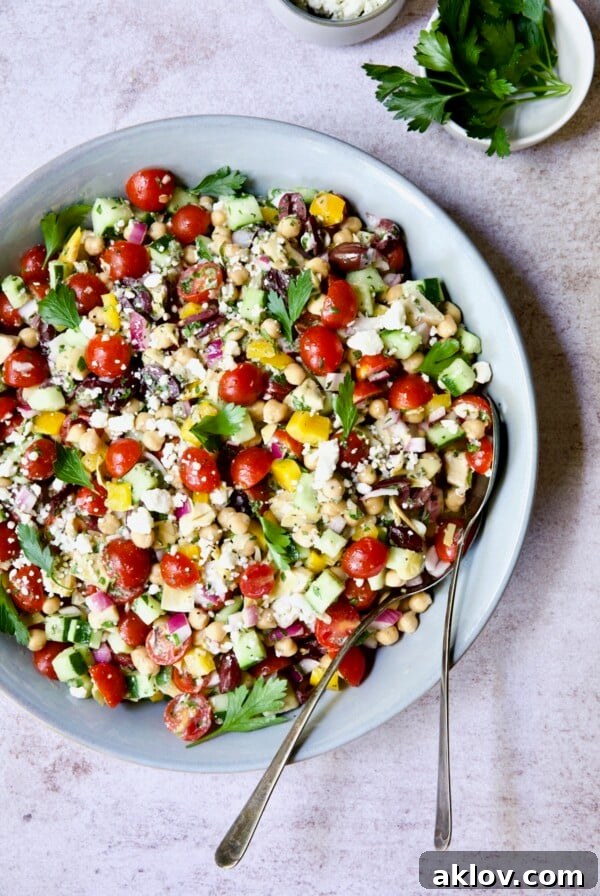 Mediterranean Chopped Salad with Chickpeas in blue serving bowl garnished with fresh parsley.
