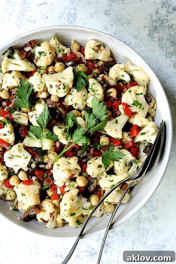 Sicilian Cauliflower Salad in white serving bowl with serving utensils.