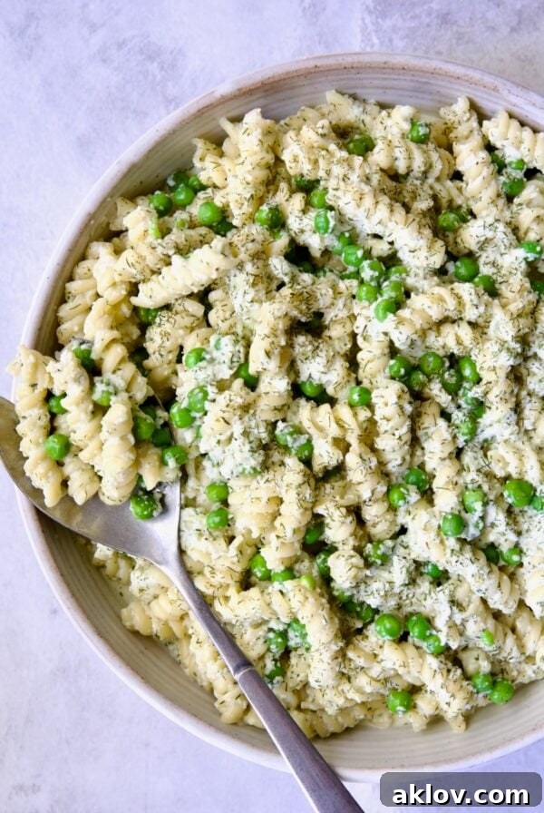 Creamy Cucumber Pasta Salad in white serving bowl with serving spoon.