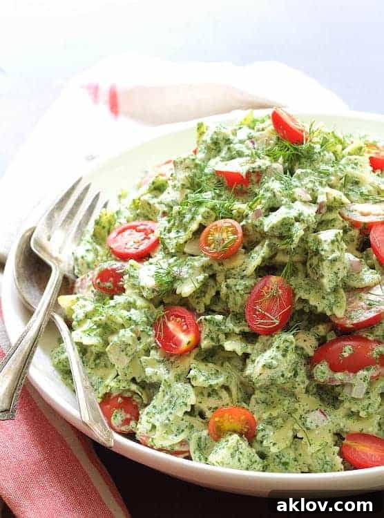 Chicken Pasta Salad with Spinach Buttermilk Dressing in white serving bowl with serving utensils.