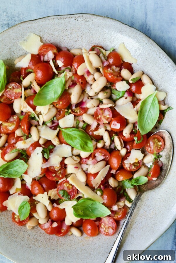 Tuscan Cherry Tomato and White Bean Salad in serving bowl with serving spoon.